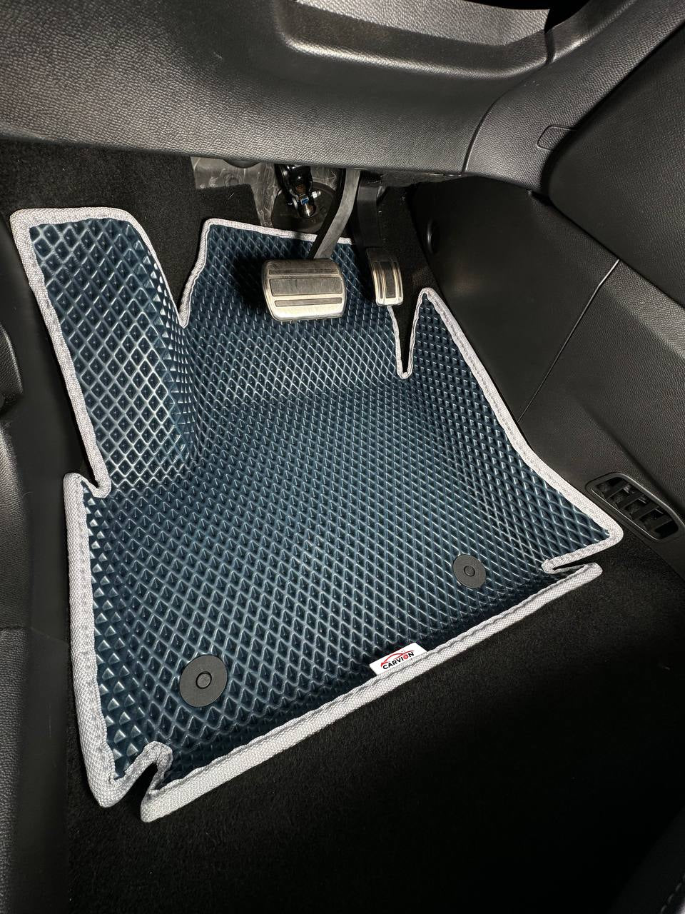 Foto illustrativa: tappetino in EVA 3D blu navy con bordi rialzati e bordo grigio nel vano piedi del guidatore